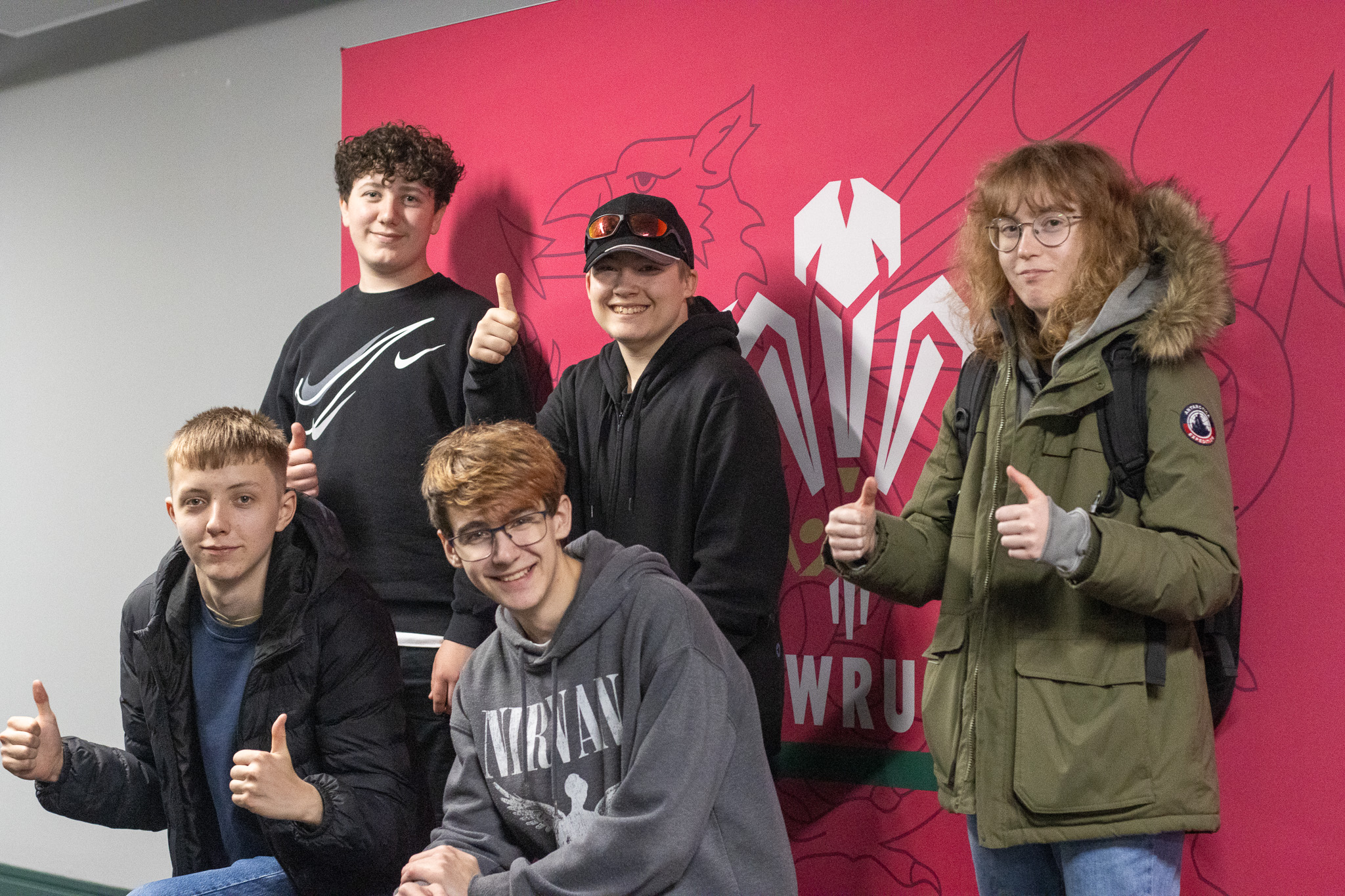 Students posing in front of the Welsh Rugby Union logo